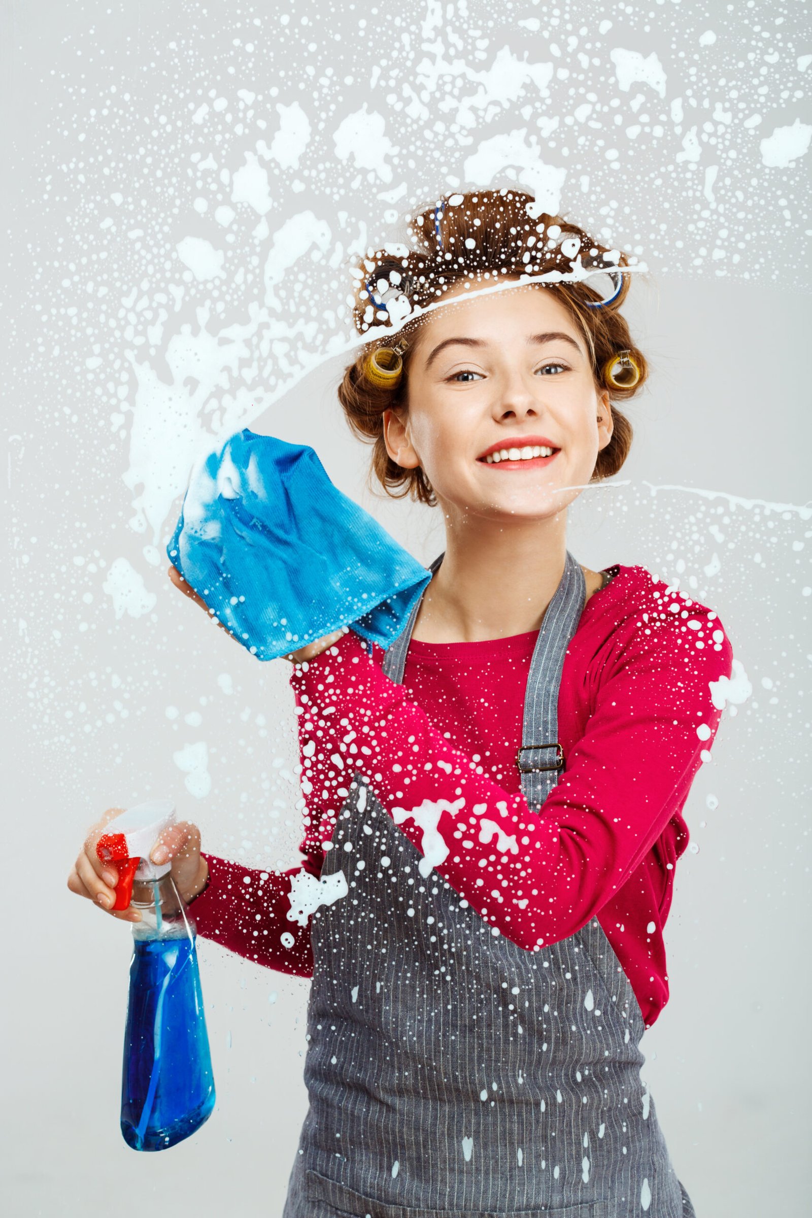 Attractive young woman washes windows and keep wide beautiful smile on face